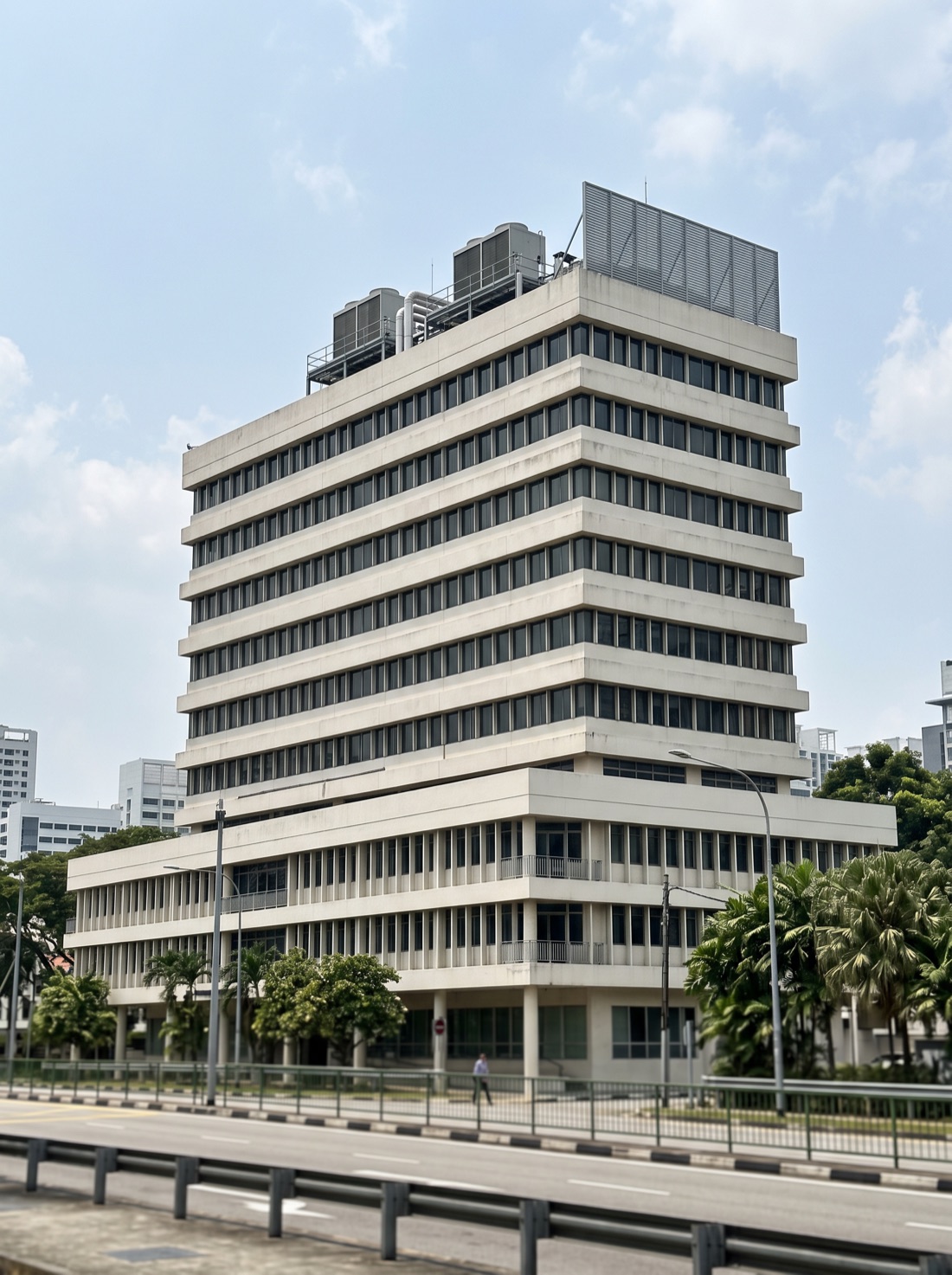 AI-generated photograph of a generic twelve-storey tropical office block: a wide three-storey podium with a taller tower rising from one end, rooftop plant visible